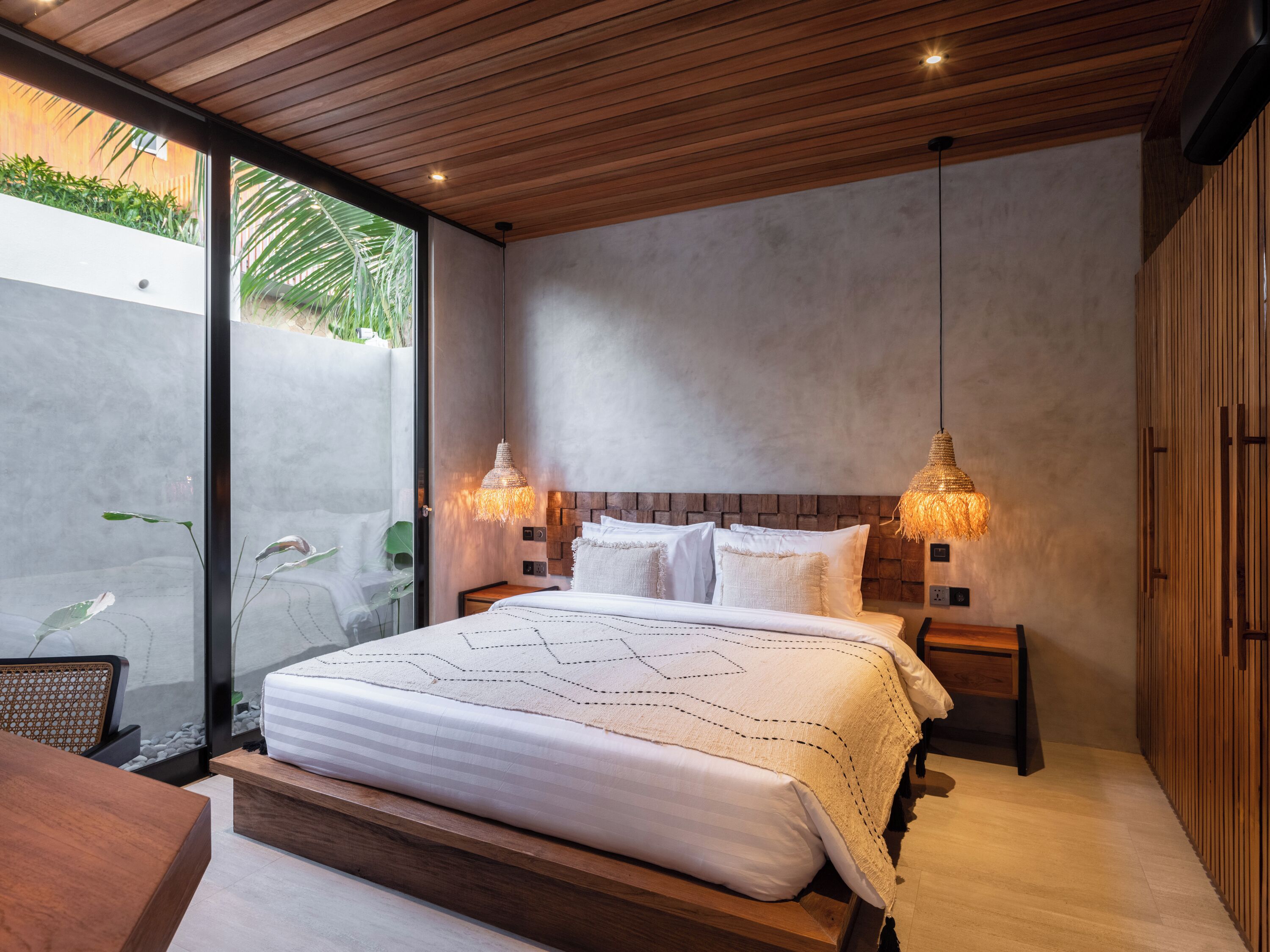 A modern bedroom with a large bed, wooden ceiling, and two bedside lamps.
