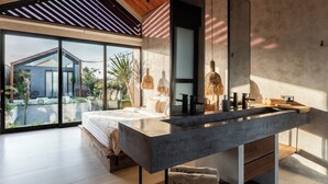 Un dormitorio moderno con una cama grande, un tocador empotrado y un amplio ventanal con vistas a un jardín.