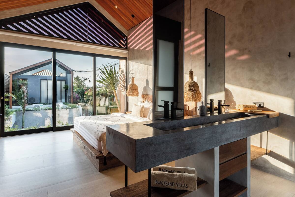 Een moderne slaapkamer met een groot bed, een ingebouwde kaptafel en een groot raam met uitzicht op een tuin.