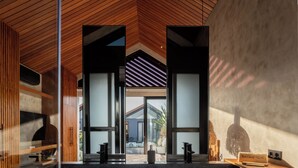 Una cocina moderna con una isla central, techo de madera y paredes de vidrio.