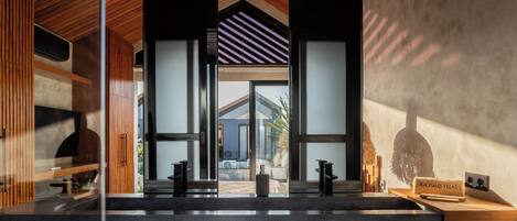 A modern kitchen with a central island, wooden ceiling, and glass walls.