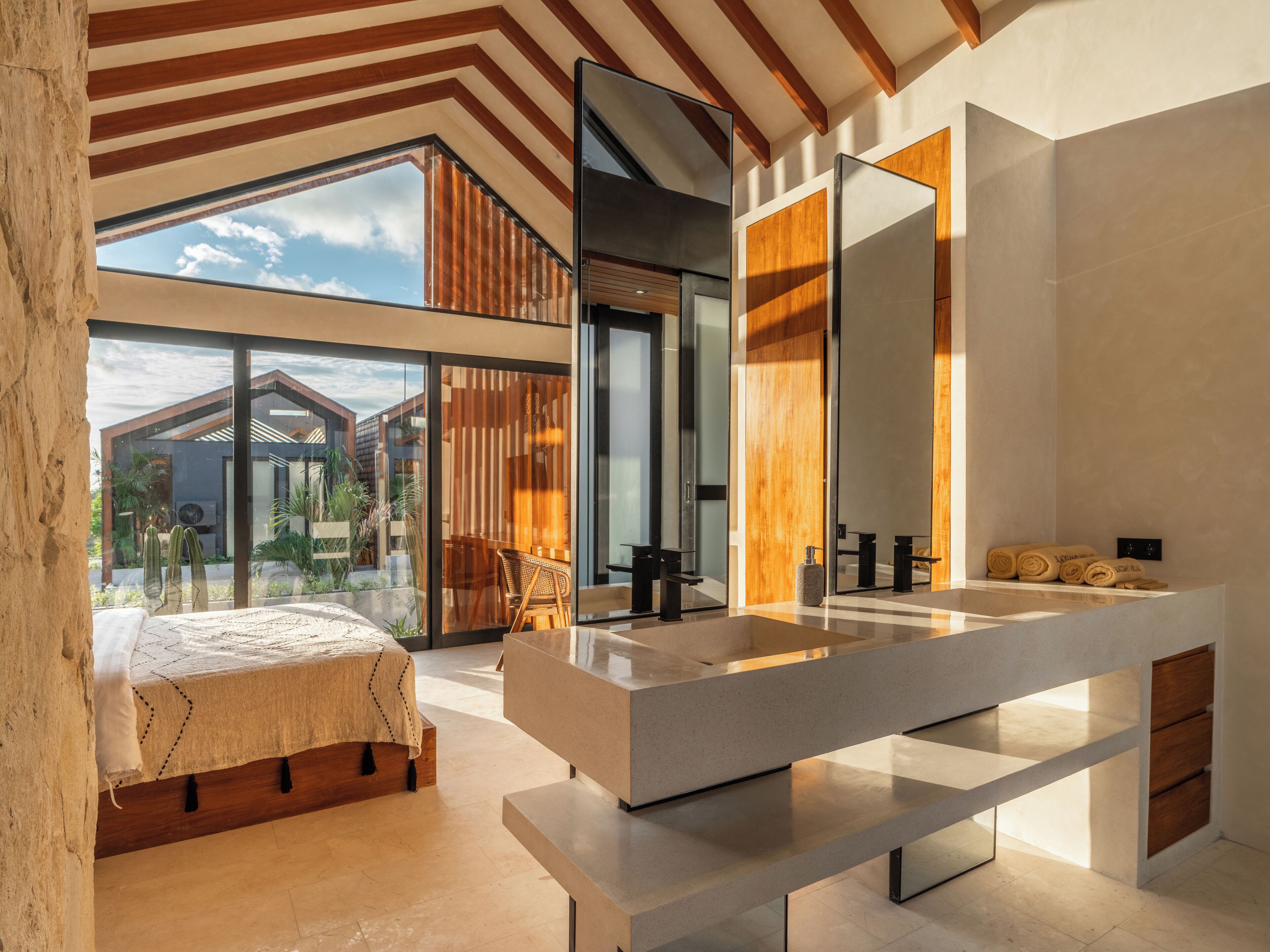 A modern bedroom with a large bed, a built-in desk, and a large mirror.