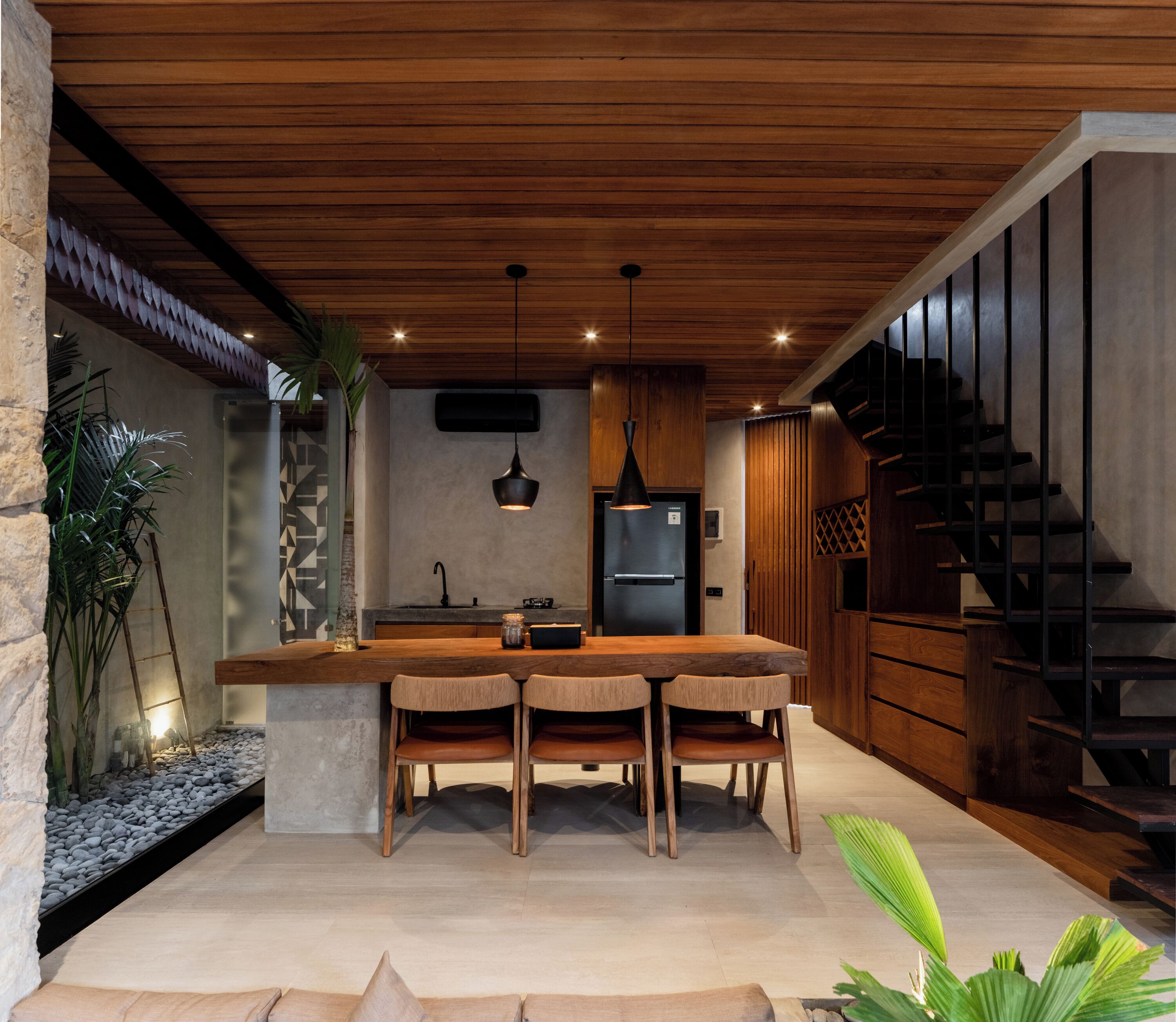 Una cocina moderna con una isla de madera, dos sillas, un refrigerador y una escalera.