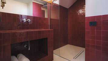 Un baño moderno con cabina de ducha de vidrio, bañera integrada y toallero.