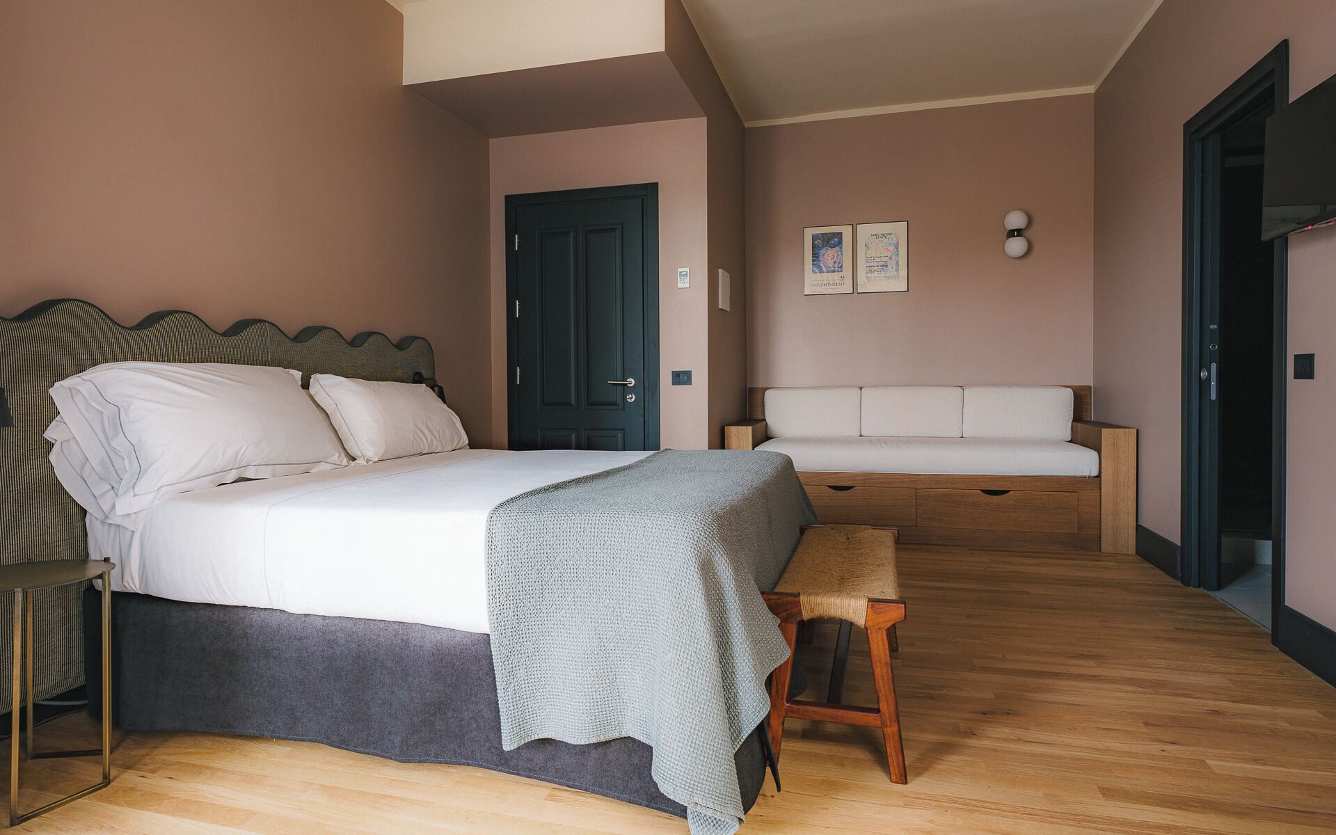 Ein Schlafzimmer mit Bett, Nachttisch, Bank und einer Couch.