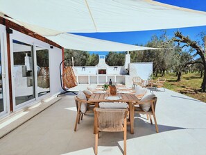 An outdoor patio with a dining table, chairs, and a hanging chair.