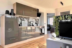 A modern kitchen with grey cabinets, a built-in oven, and a coffee machine. - Brand new modern apartment suitable for fitters (Bensheim)