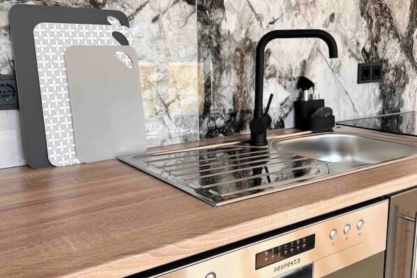 A modern kitchen with a built-in stove, a sink, and a marble backsplash. - Brand new modern apartment suitable for fitters (Bensheim)