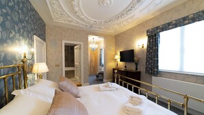 A well-appointed bedroom with a large bed, a television, and a view of the outside.