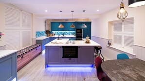 A modern kitchen with a central island, pendant lights, and a built-in oven.