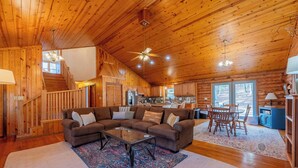 A spacious living room with a large sectional sofa, a glass coffee table, and a wooden ceiling.