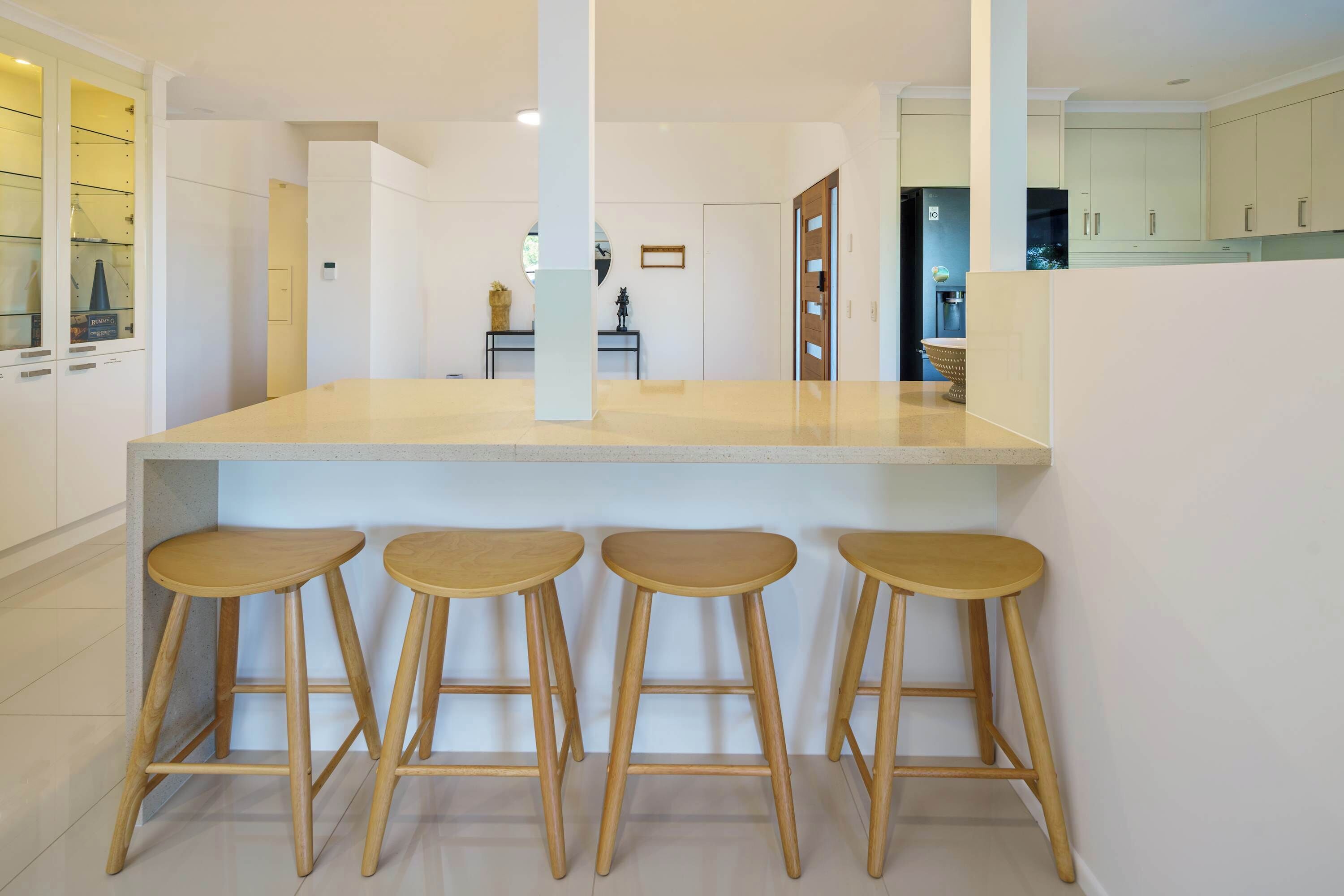 Een moderne keuken met een centraal eiland, barkrukken en uitzicht op de eetruimte.