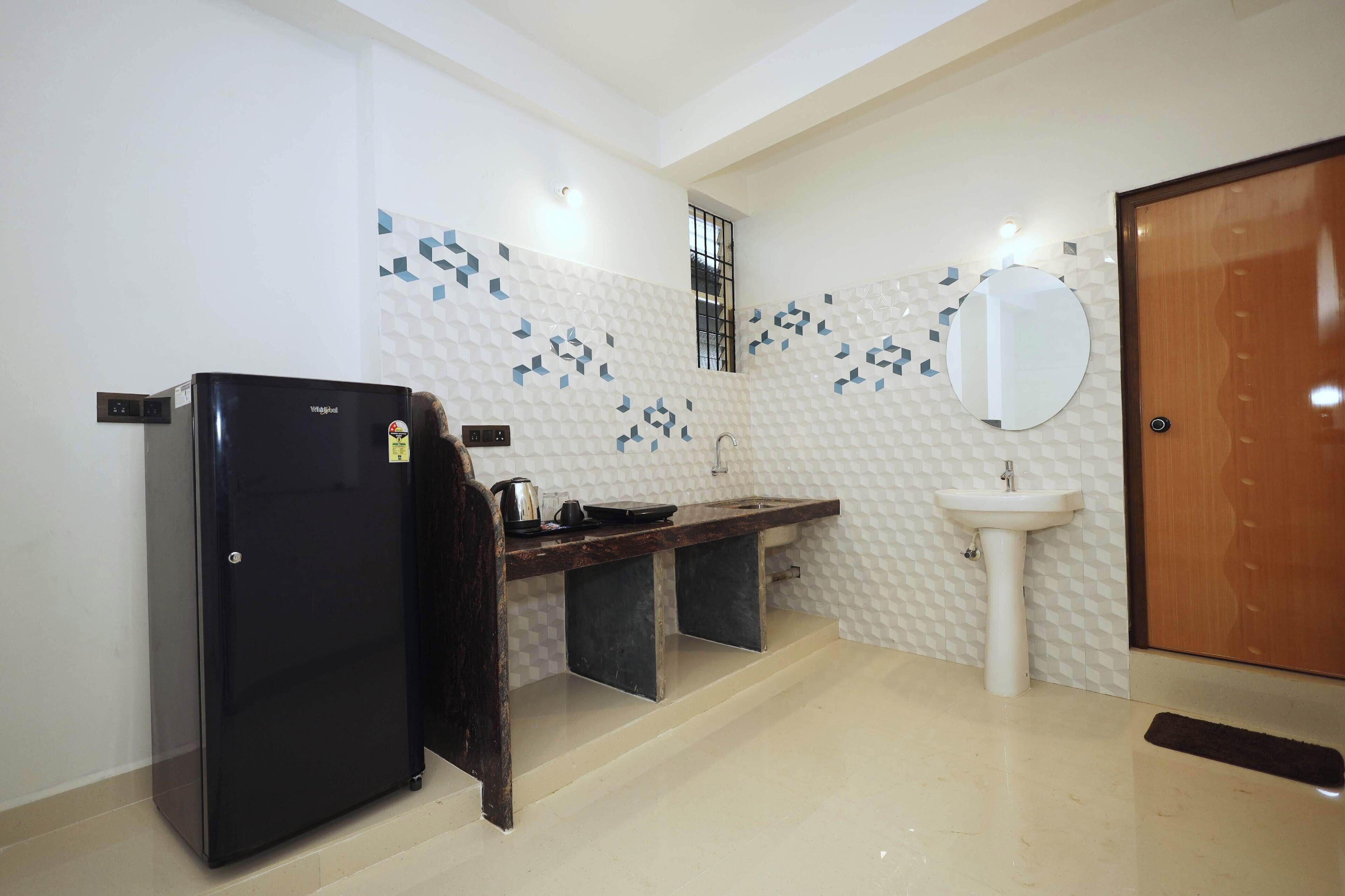 A compact kitchen with a refrigerator, sink, and a small window.