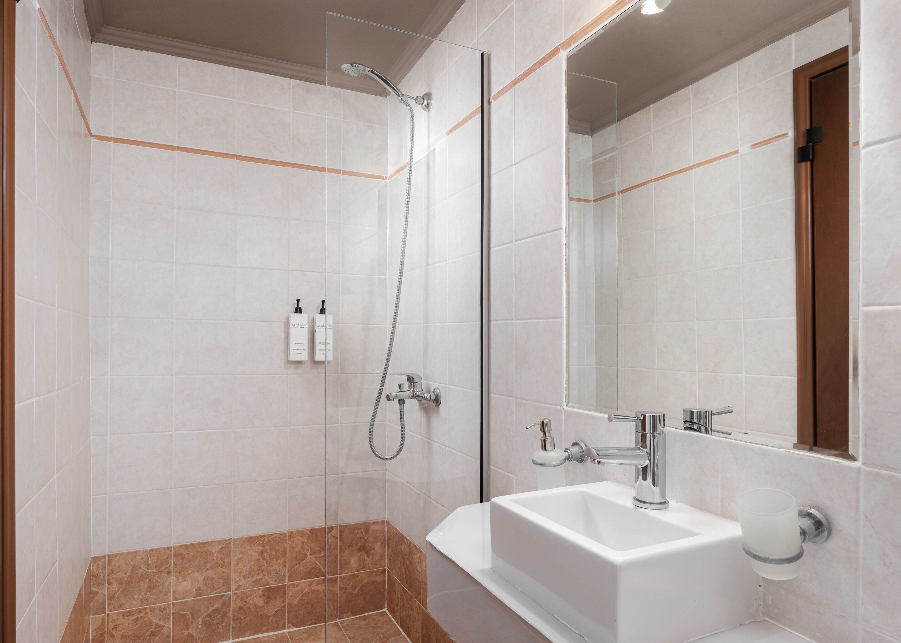 A modern bathroom with a shower, a sink, and a mirror.