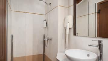 Un baño con cabina de ducha de vidrio, un lavamanos blanco y un secador de pelo fijado a la pared.