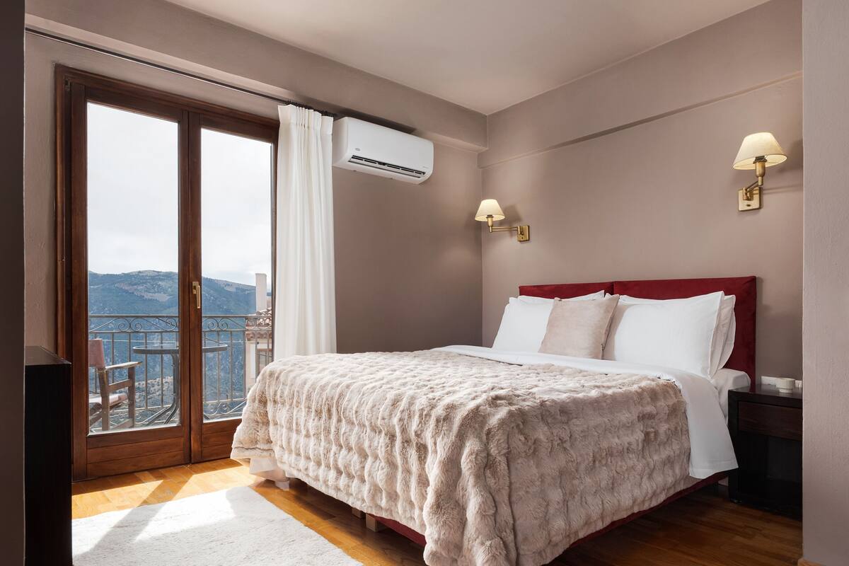 Une chambre avec un grand lit, une vue sur l’extérieur et un balcon.