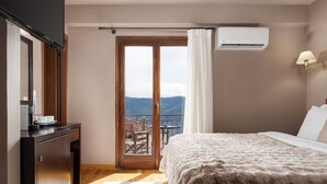 Ein Schlafzimmer mit Bett, Schreibtisch, Stuhl, einem Fenster mit Vorhängen und einer Klimaanlage.