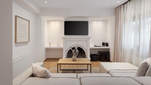 Ein modernes Wohnzimmer mit Kamin, einem darüber angebrachten Flachbildfernseher und einer Sofagarnitur.