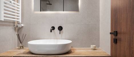 A modern bathroom with a large white sink, a wooden countertop, and a mirror above the sink.