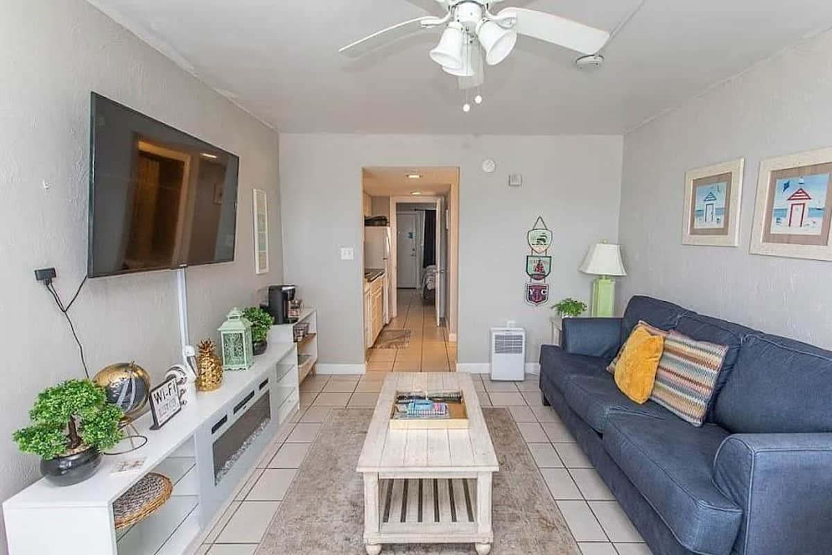 A living room with a TV, sofa, coffee table, and decorative items.