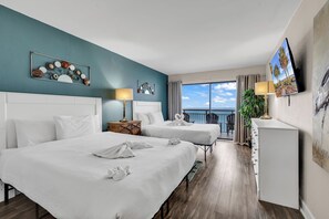 A hotel room with two beds, a desk, a TV, and a balcony with a view of the ocean. - Bluewater Resort Condos (Myrtle Beach)