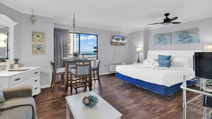 A hotel room with a bed, a desk, a dining table, and a TV.