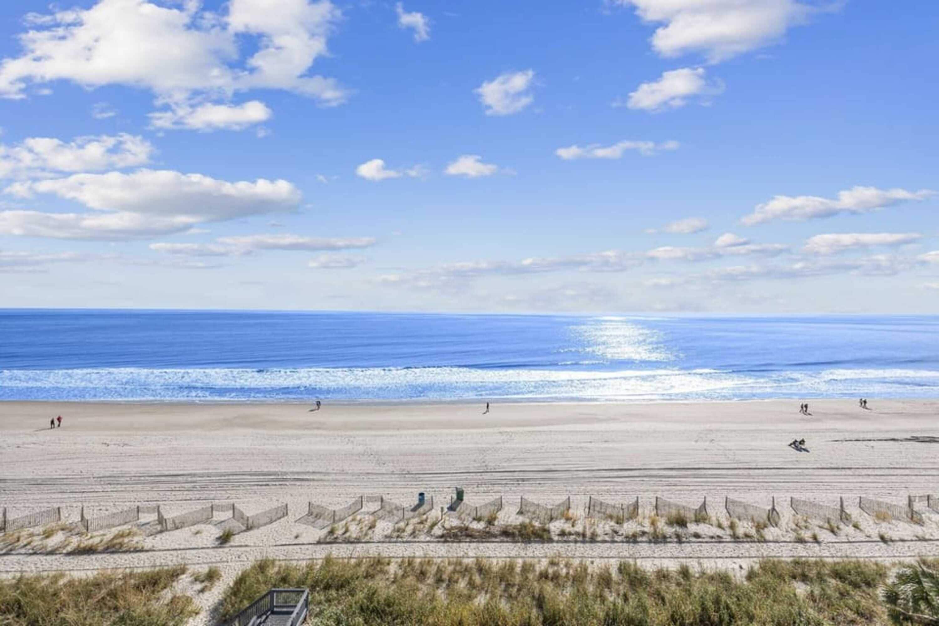 A beach with a clear sky, calm sea, and a sandy shore.