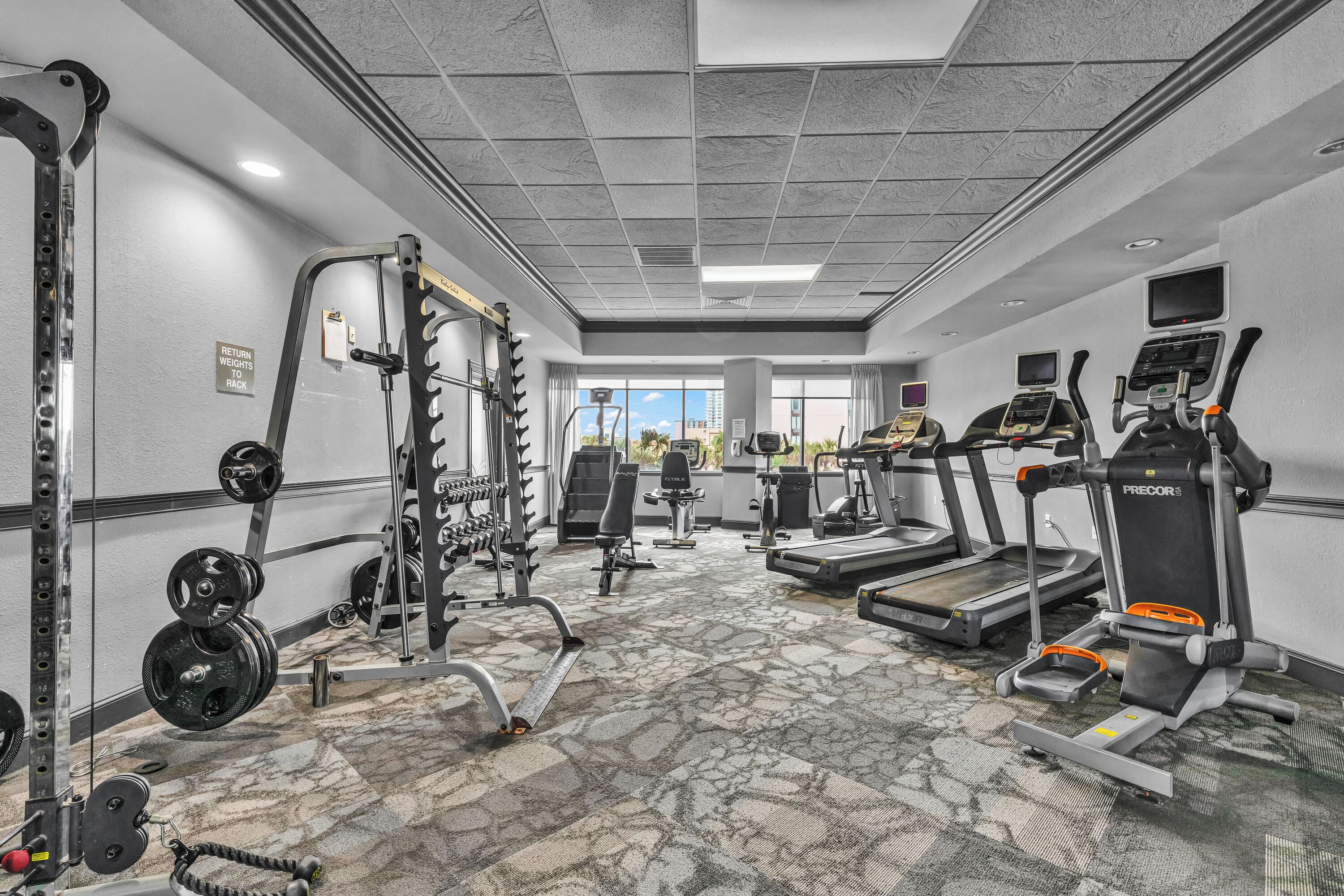Ein Fitnessstudio mit Laufbändern, Crosstrainern und Kraftgeräten.