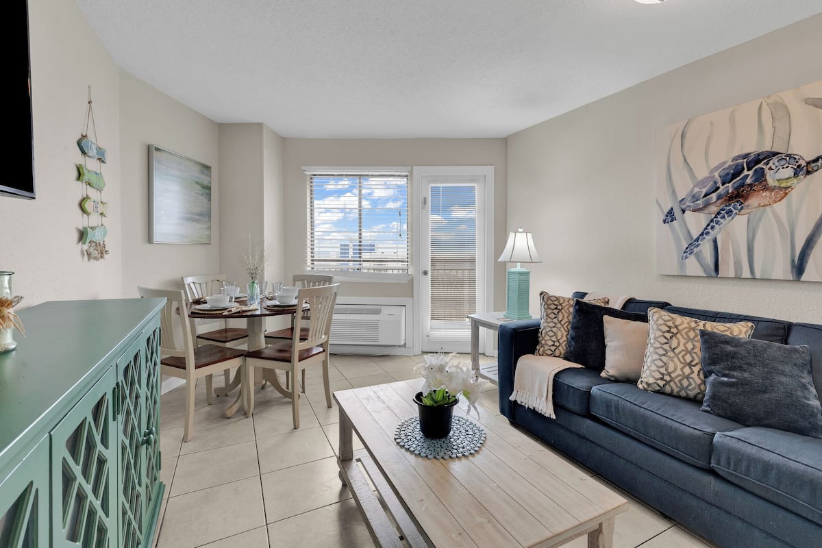 A living room with a dining area, a sofa, a coffee table, and a TV.