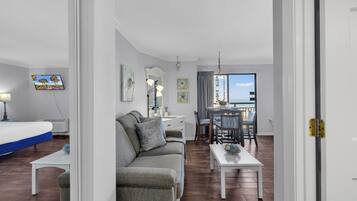 A modern living room with a sofa, a dining table, and a TV.