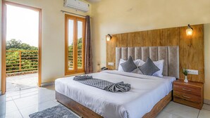 Un dormitorio con una cama grande, cabecera de madera, mesitas de noche y vistas a zonas verdes a través de un ventanal corredero.