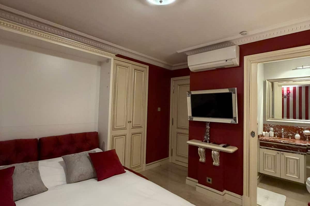 Une chambre dotée d’un grand lit, d’une télévision, d’une coiffeuse avec un miroir et d’un appareil de climatisation.