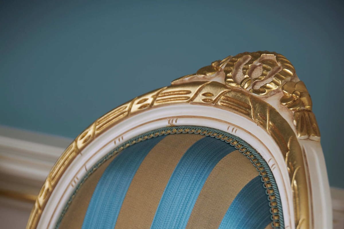 Une chaise dotée d’un coussin à rayures et d’une garniture dorée décorative.