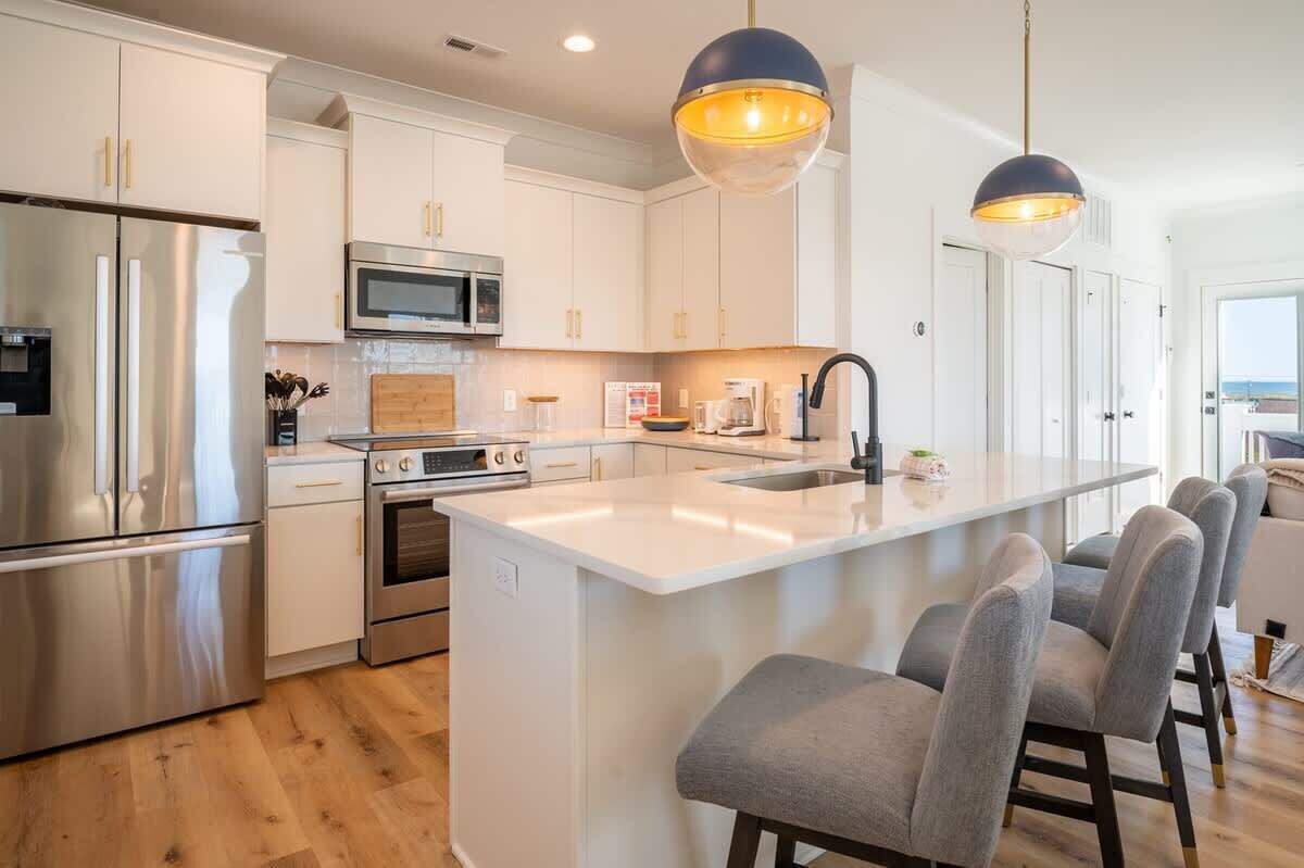 A modern kitchen with stainless steel appliances, a central island, and bar-style seating.