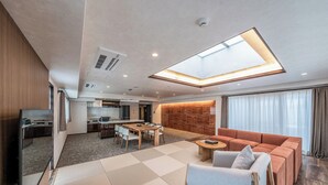 A modern hotel room with a dining area, a sofa, and a large window. - Apartment Hotel 11 Namba Motomachi (Osaka)