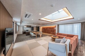 Une chambre d’hôtel moderne dotée d’un coin repas, d’un canapé et d’une grande fenêtre.