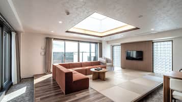 A modern living room with a sectional sofa, a coffee table, and a flat-screen TV mounted on the wall.