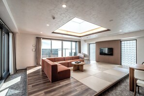 Ein modernes Wohnzimmer mit einem Ecksofa, einem Couchtisch und einem flachbildfernseher an der Wand.