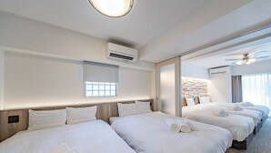 Ένα δωμάτιο ξεν οδοχείου με τρία κρεβάτια, το καθένα με λευκά σεντόνια και πετσέτες, έναν μεγάλο καθρέφτη και έναν ανεμιστήρα οροφής.