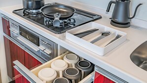 A modern kitchen with a gas stove, a kettle, and a drawer with utensils. - Apartment Hotel 11 Namba Motomachi (Osaka)