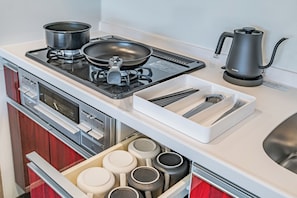 Une cuisine moderne équipée d’une cuisinière à gaz, d’une bouilloire et d’un tiroir contenant des ustensiles de cuisine.
