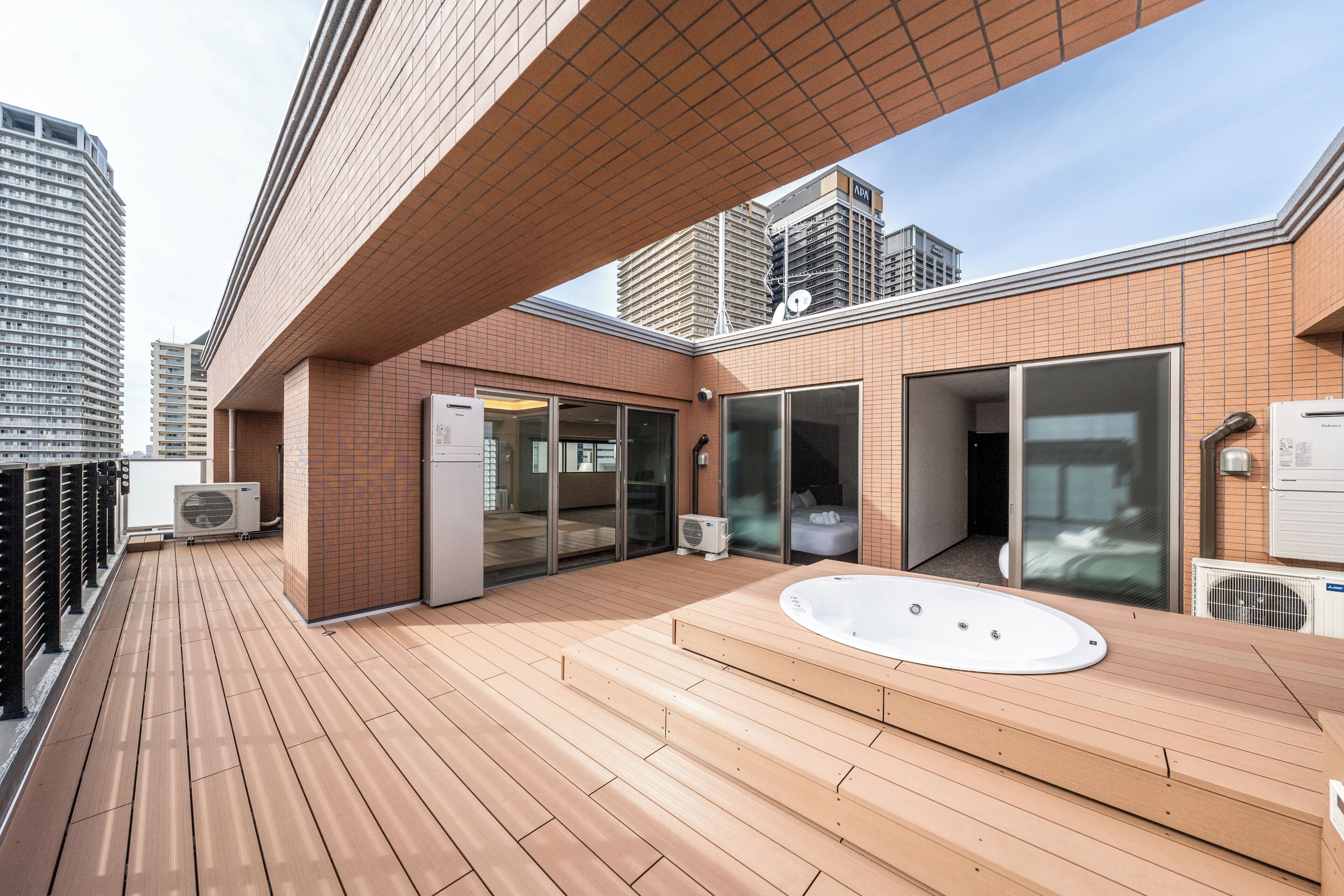 En tagterrasse med træterrasse, jacuzzi og et rum med glasfacade.