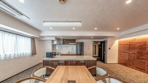 Una cucina moderna con isola centrale, elettrodomestici integrati e zona pranzo con tavolo e sedie in legno.