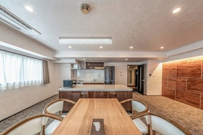 Una cocina moderna con una isla central, electrodomésticos integrados y un comedor con mesa y sillas de madera.