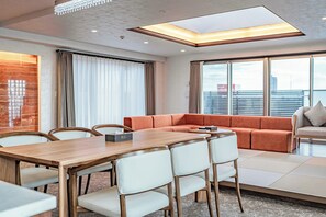 Una habitación de hotel moderna con comedor, sofá y vistas a la ciudad.