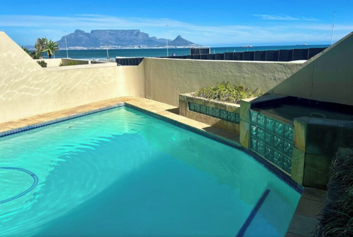 A swimming pool with a view of the ocean and mountains.