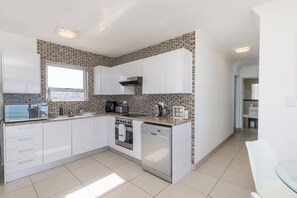 A modern kitchen with white cabinets, a built-in oven, and a dishwasher.