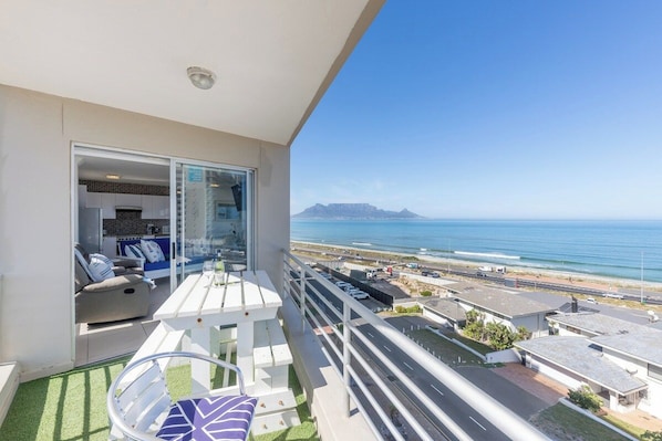 A balcony with a view of the ocean and a distant mountain range.