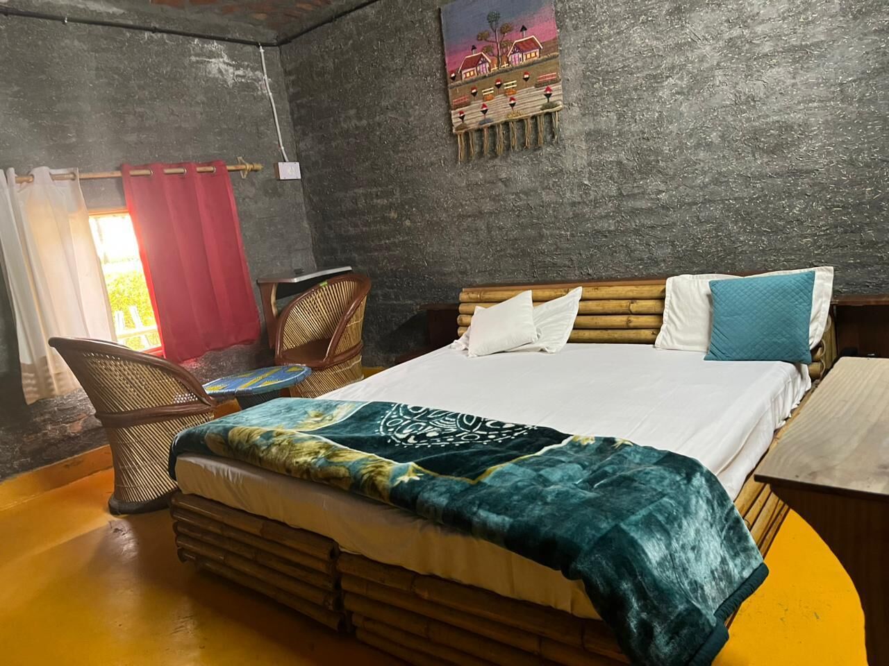A bedroom with a bed, a chair, a table, and a painting on the wall.