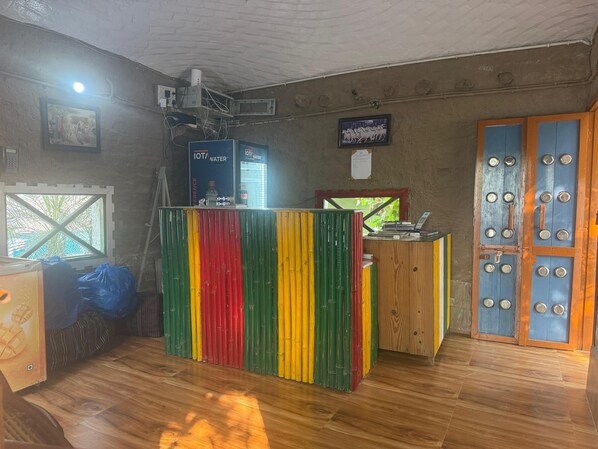 Een receptiebalie met een kleurrijk gestreept ontwerp, een houten deur met ronde handgrepen, en een raam met uitzicht op groen.